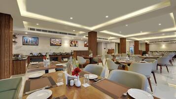 A modern dining area with multiple tables, chairs, and a buffet setup.