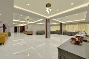 A spacious hotel lobby with a marble floor, seating areas, and a reception desk.