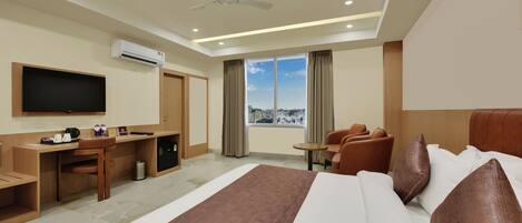 A hotel room with a bed, a desk, a chair, a television, and a window with a city view.