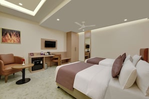 Ein Hotelzimmer mit einem Bett, einem Schreibtisch, einem Sessel, einem Fernseher und einem Deckenventilator.
