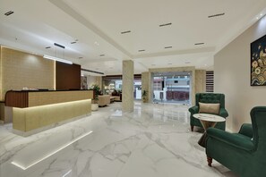 A hotel lobby with a reception desk, seating area, and a view of the hotel exterior. - Vaishnavi Beacon Hotel Patna (Patna)