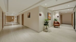 A hotel corridor with a no-smoking sign, a potted plant, and a leather chair. - Vaishnavi Beacon Hotel Patna (Patna)
