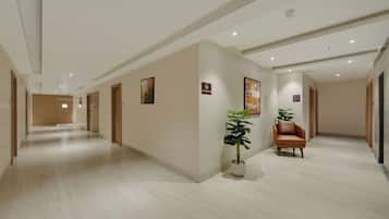 A hotel corridor with a no-smoking sign, a potted plant, and a leather chair.