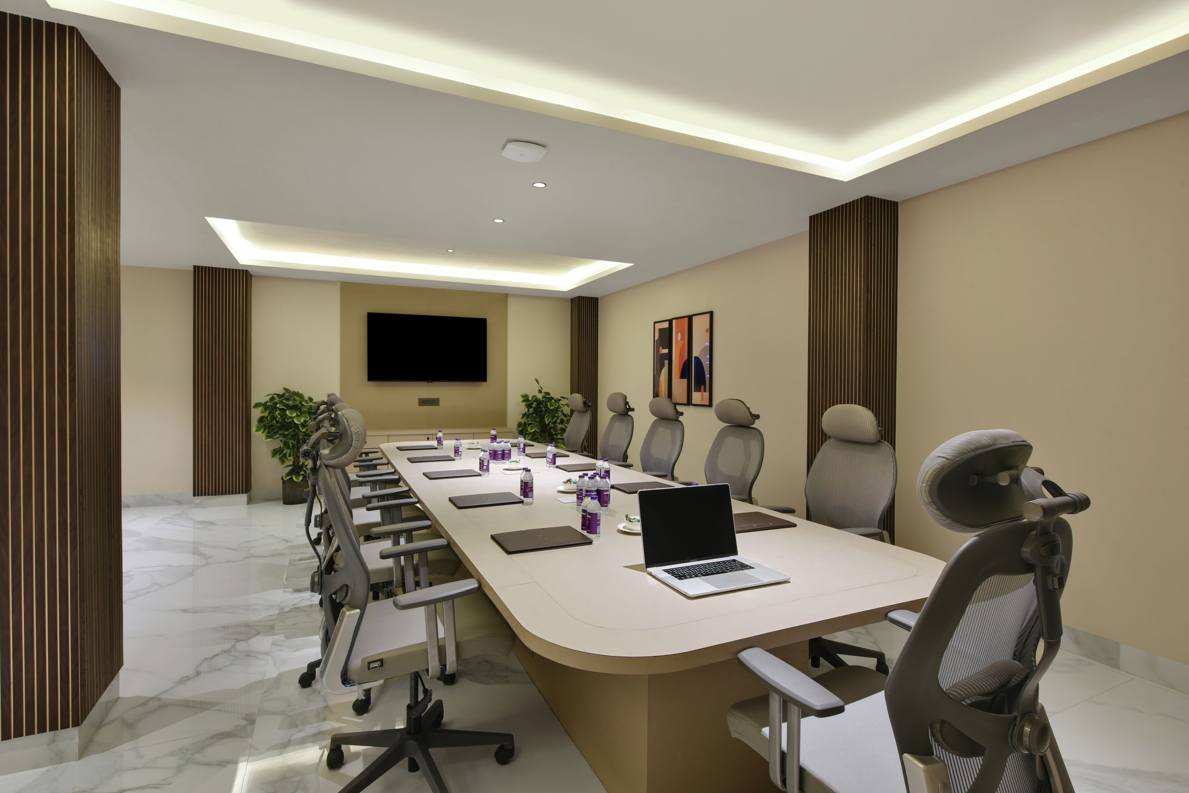 A conference room with a long table, chairs, a laptop, and water bottles.