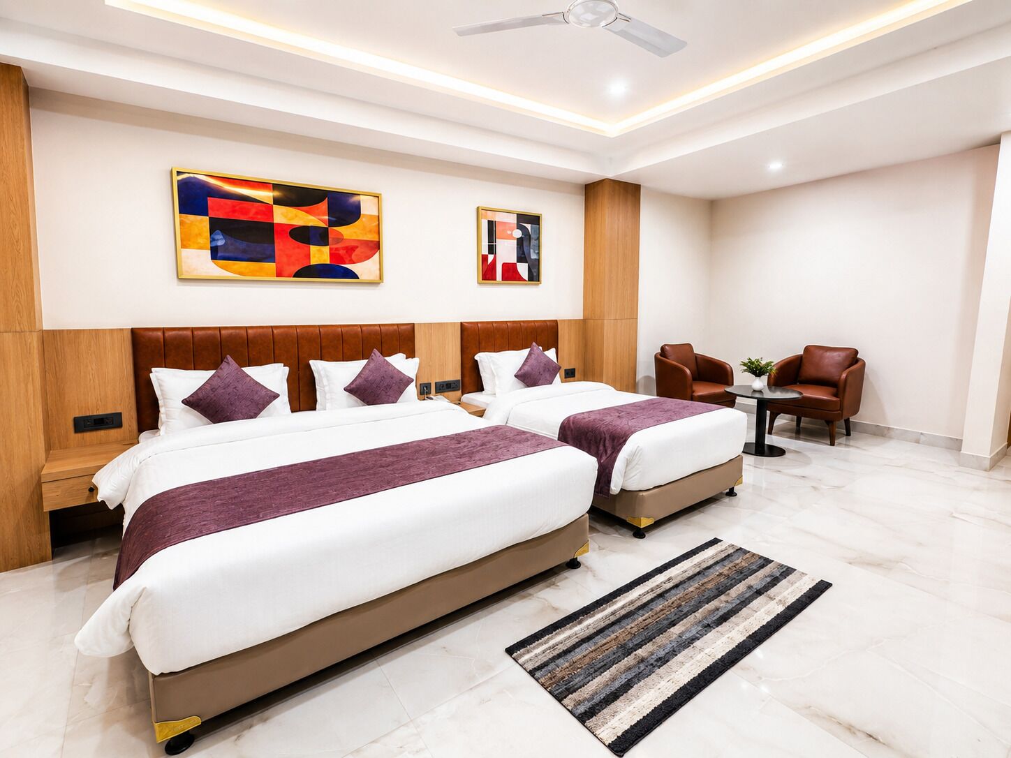 Una habitación de hotel moderna con dos camas, una zona de estar y obras de arte en las paredes.