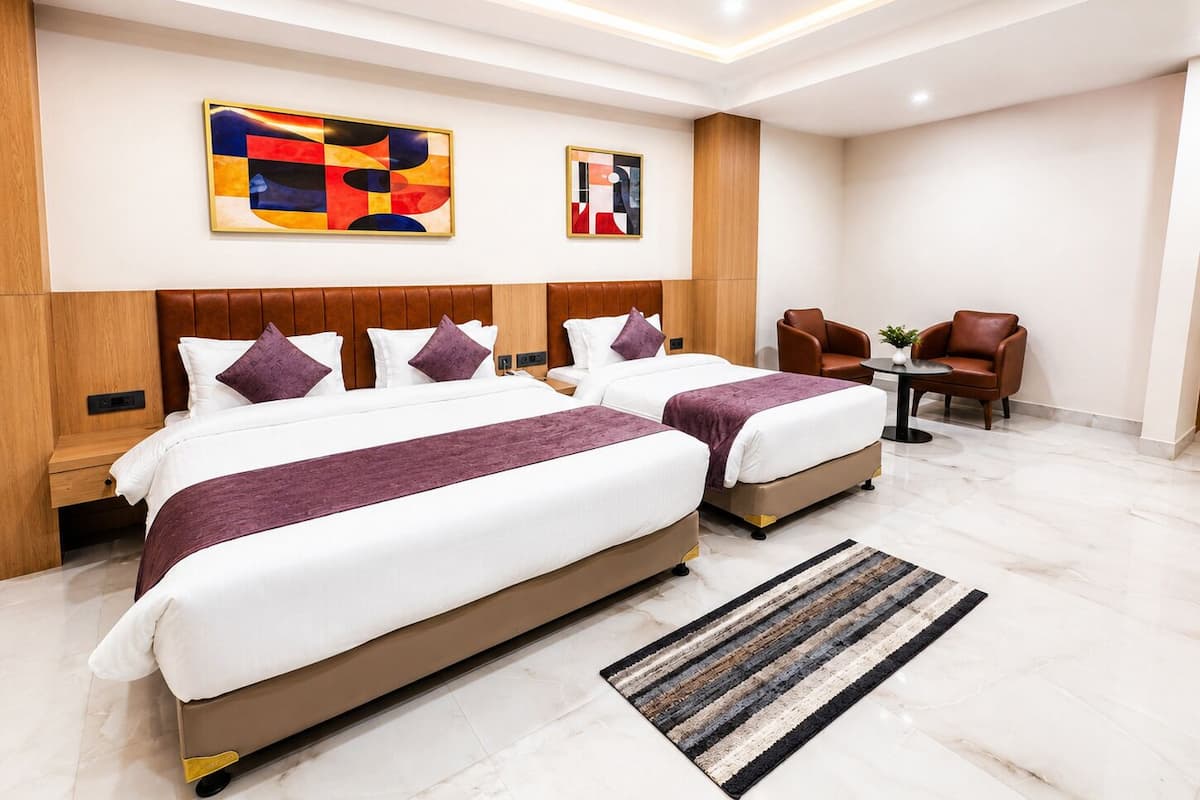 A modern hotel room with two beds, a seating area, and artwork on the walls.