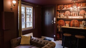 Ein gemütlicher Raum mit einem braunen Ledersofa, einer Bar mit Holzfässern und einer Chandelier.