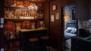 Eine Bar mit einer Deckenleuchte, Weinfassregalen und einem Neonlichtschild mit der Aufschrift 'THE GARRISON'.