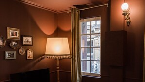 Ein Wohnzimmer mit Fernseher, Lampe, Sofa, Teppich und einem fenster mit Vorhängen.