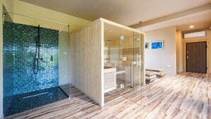 Un baño moderno con cabina de ducha de vidrio, paneles de madera y suelo de madera.
