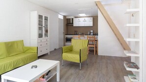 A compact living space with a kitchenette, a dining area, and a staircase. - Buitenplaats Herkingen 25-A (Herkingen)