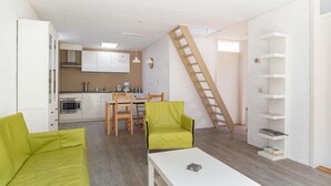 A compact living space with a kitchen, dining area, and a loft bedroom accessed by a wooden ladder. - Buitenplaats Herkingen 25-A (Herkingen)