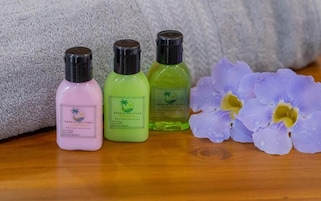 Tres botellas de líquido sobre una superficie de madera con una toalla y una flor.