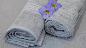 Two rolled towels with a purple flower placed on top. - Sand & Sea Villa  (Negombo)