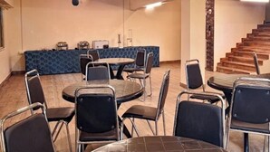 A conference room with round tables and chairs, a blue patterned wall, and a staircase. - Hotel Bella Casa (Gangtok)
