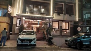 A building with a staircase leading to the entrance, a parked car, and a motorcycle. - Hotel Bella Casa (Gangtok)