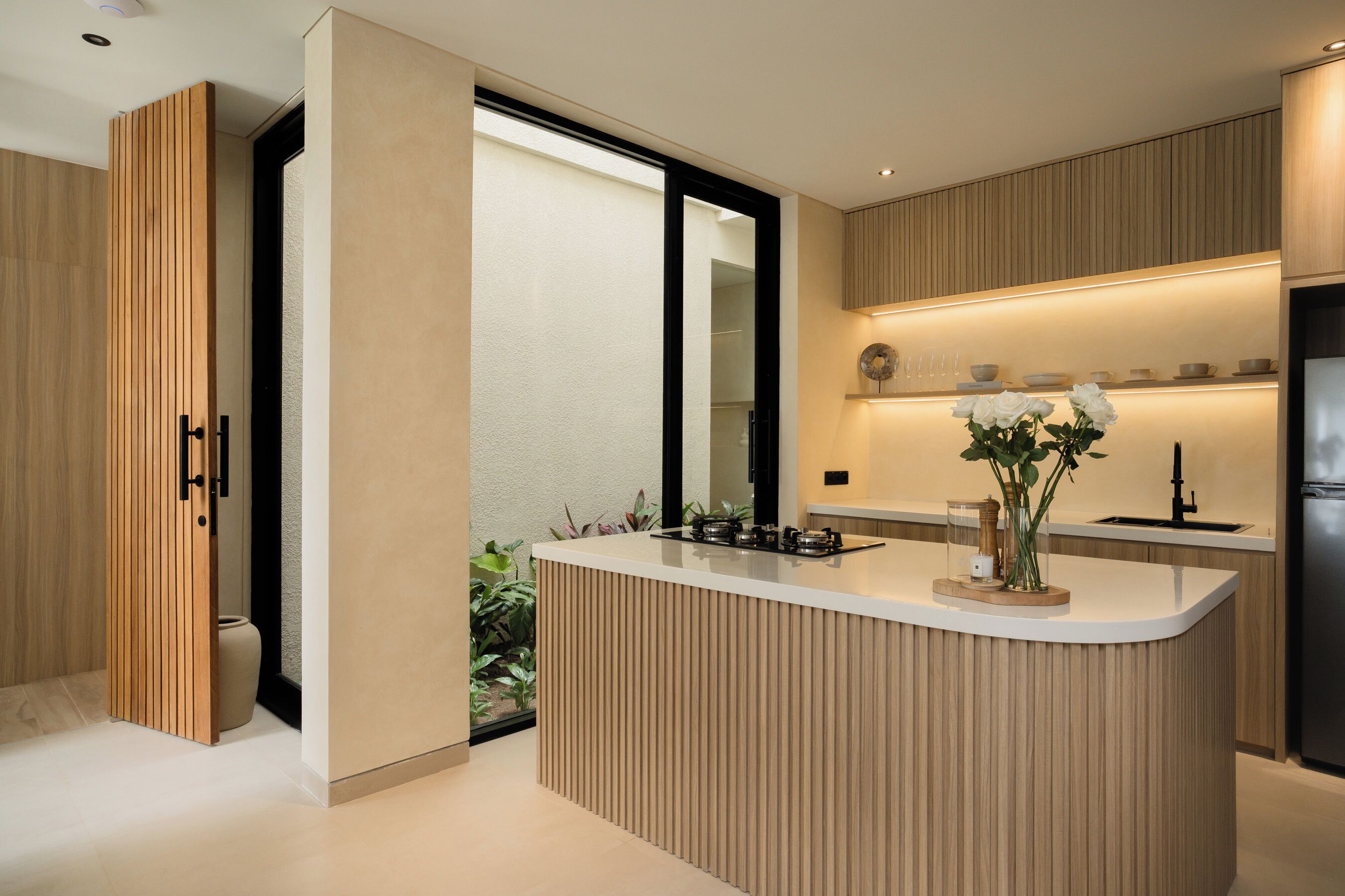 Une cuisine moderne dotée d’un îlot central, de meubles en bois et d’un four encastré.