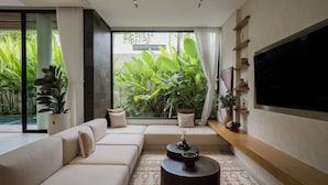 A modern living room with a sofa, a coffee table, and a TV mounted on the wall. - KONO Villas & Resort (Kutuh)