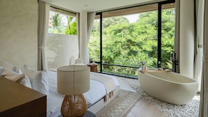 A modern bedroom with a large window, a bathtub, a bed, and a bedside table. - KONO Villas & Resort (Kutuh)