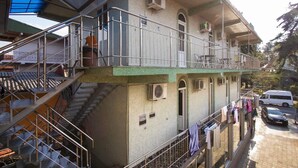 Ein mehrstöckiges Gebäude mit Treppe, Balkonen und einem geparkten Fahrzeug davor.