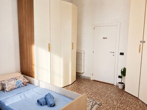 Une chambre à coucher avec un lit, une armoire, un radiateur et une plante en pot.