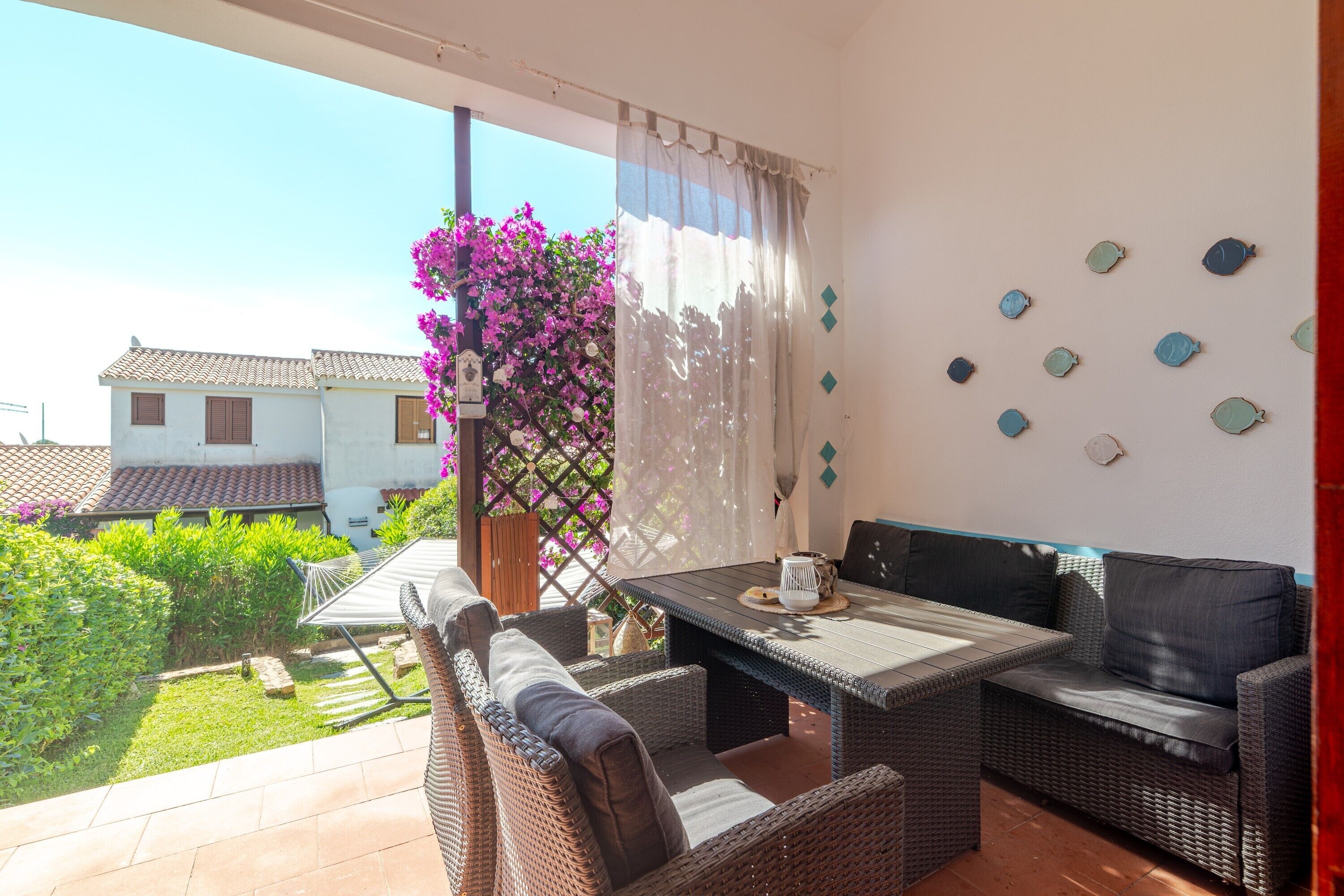 Un balcone con mobili in vimini, un tavolo e vista su una casa e un giardino.