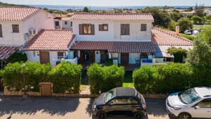 A residential building with a tiled roof, a driveway, and parked cars. - Apartment 'Sole-mare' with Sea View, Wi-Fi and Air Conditioning (Porto Ottiolu)