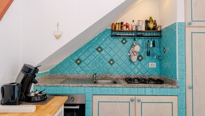 A kitchen with a blue tiled backsplash, a coffee maker, a sink, and a stove. - Apartment 'Sole-mare' with Sea View, Wi-Fi and Air Conditioning (Porto Ottiolu)