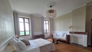 Een slaapkamer met een bed, nachtkastje, lamp, houten vloer en een hangende lamp.