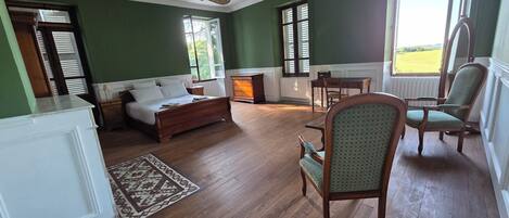 Una habitación con cama, una silla, una mesa y chimenea.