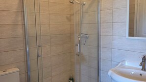 Een badkamer met een douchecabine, een toilet en een wastafel.
