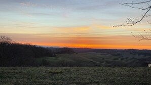 Een landschap met glooiende heuvels en een zonsondergang.