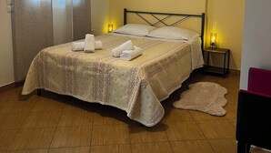 A bedroom with a bed, bedside lamps, a painting, a mirror, and a door. - Bright & Elegant Apartment - Comfort & Style in Piraeus (Pireas)