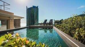 A swimming pool with lounge chairs, a high-rise building in the background, and a clear sky. - Pool Monte Carlo Luxury Apartment (Beausoleil)