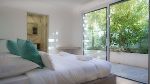 A modern bedroom with a large bed, a glass door leading to a balcony, and a view of greenery outside. - Pool Monte Carlo Luxury Apartment (Beausoleil)