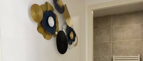 A modern bathroom with a washing machine, a towel rack, and decorative wall art.
