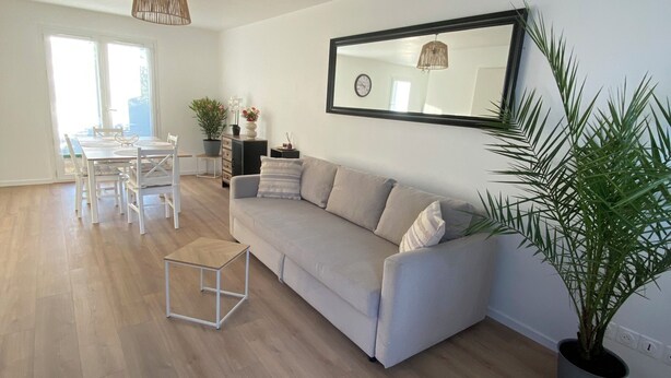 A modern living room with a sofa, dining table, and chairs, a large mirror, and a potted plant. - House for rent Audierne (Audierne)