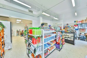 Ein Gang in einem Supermarkt mit Regalen voller Getränke, Snacks und Haushaltsartikeln.