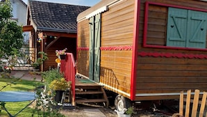 A wooden mobile home with a red exterior, a small porch, and a staircase leading to the entrance. - Agnès's garden caravan 37150 (Luzillé)