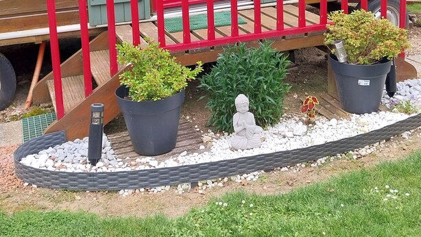 A wooden building with a red door and green shutters, a small porch with a red railing, and potted plants. - Agnès's garden caravan 37150 (Luzillé)