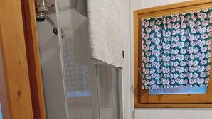 A bathroom with a glass shower enclosure, a wooden cabinet, a sink, and a toilet. - Agnès's garden caravan 37150 (Luzillé)