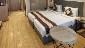 A hotel room with a large bed, bedside tables, a small round table, and a wardrobe. - Orana Hotel & Convention ,Vaishali 1 minute Walk from Vaishali Metro Station. (Ghaziabad)