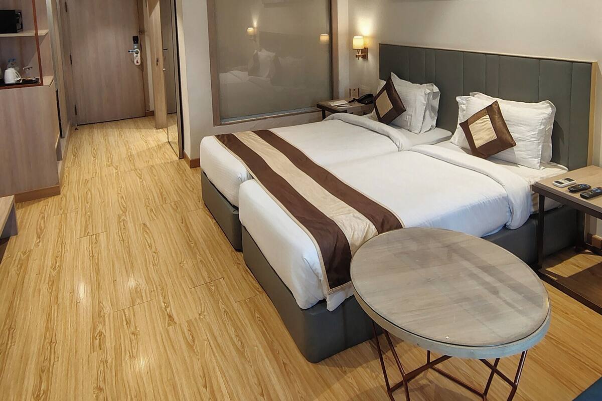 A hotel room with a large bed, bedside tables, a small round table, and a wardrobe.