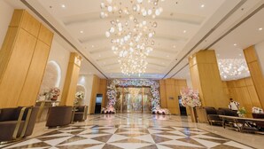 A hotel lobby with a checkered floor, a chandelier, and wooden paneling. - Orana Hotel & Convention ,Vaishali 1 minute Walk from Vaishali Metro Station. (Ghaziabad)