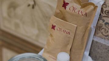 A bathroom with a marble sink, a bottle of hand soap, and paper towels branded with 'ORANA HOTEL & CONVENTION'.
