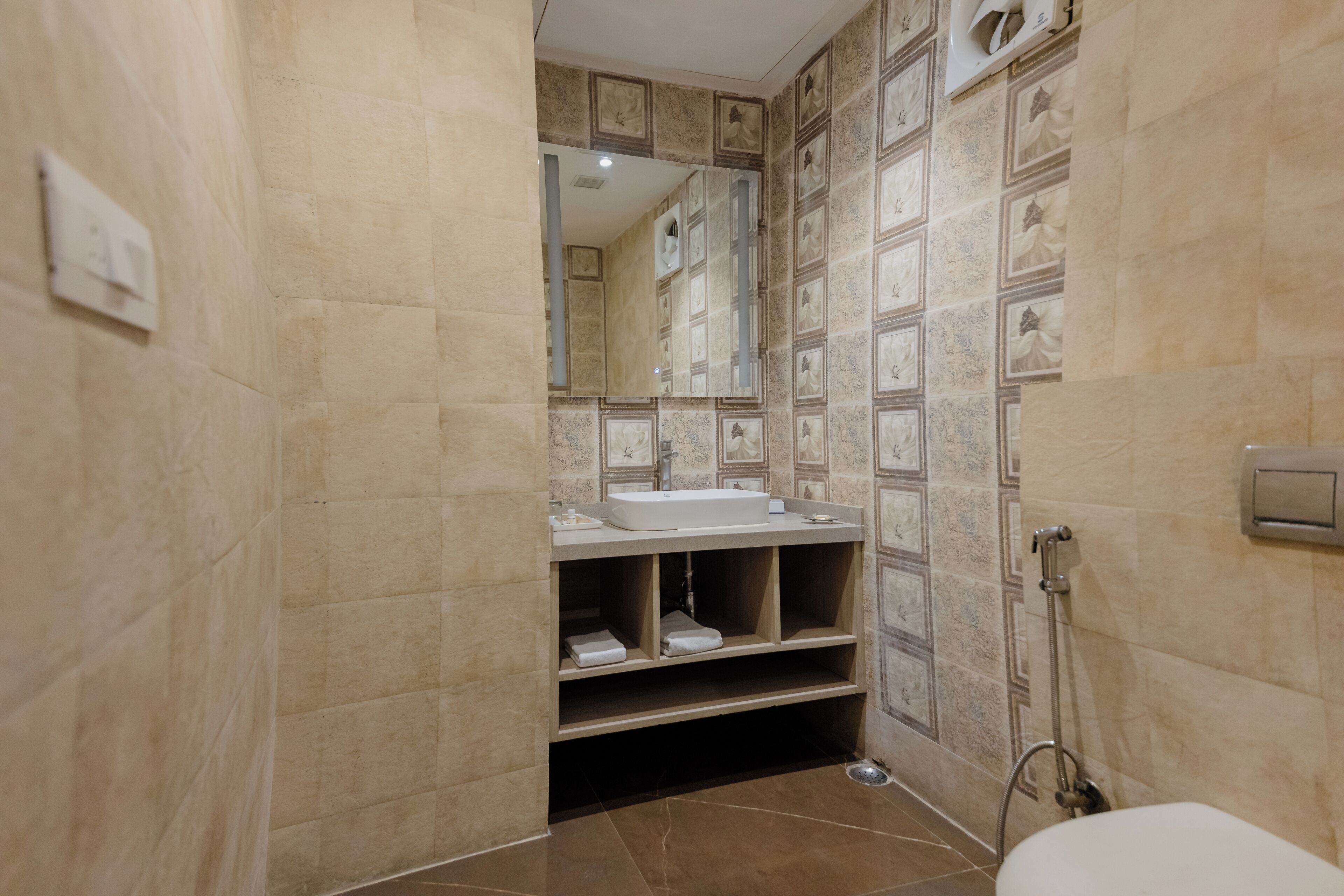 Un baño con lavamanos, espejo, repisas y ducha.