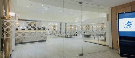 A modern interior with glass partitions, a reception desk, and a digital screen displaying the hotel name.