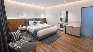 Habitación de hotel moderna con una cama grande, mesitas de noche, un escritorio, una silla, un espejo y un armario.