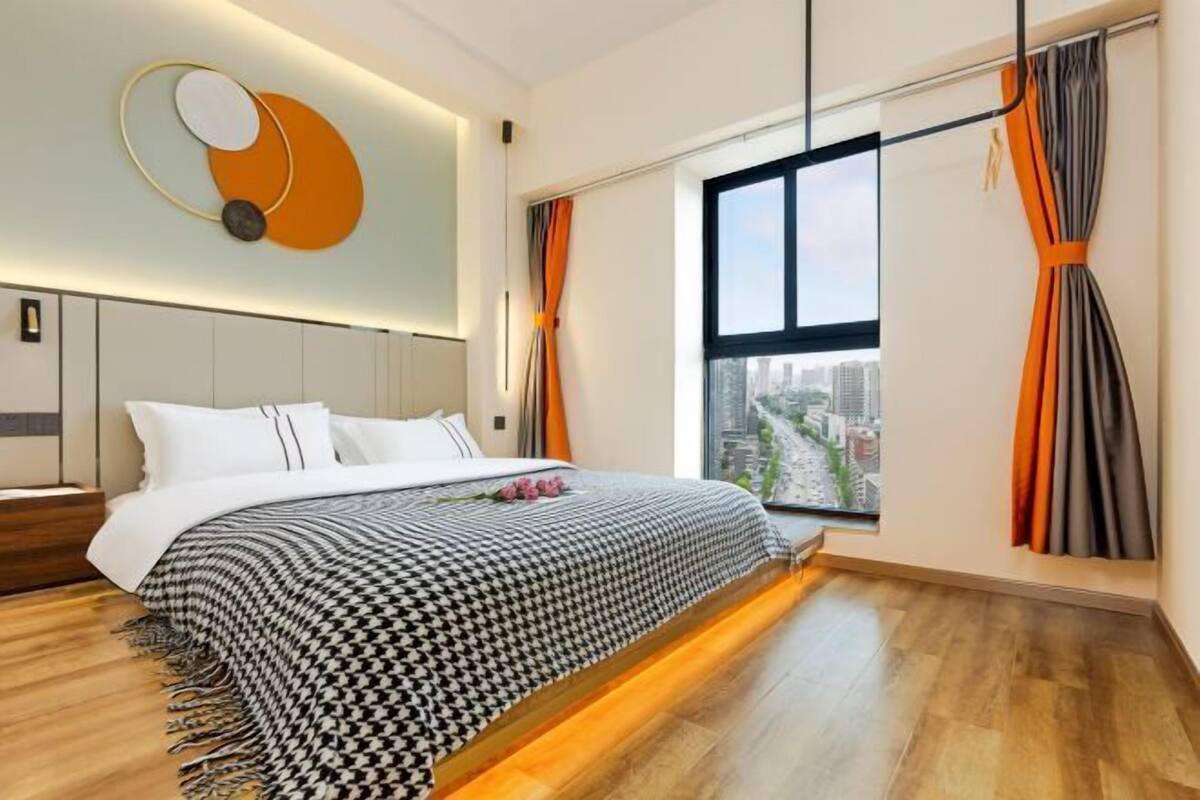 A modern bedroom with a large bed, a city view, and a unique wall art piece.
