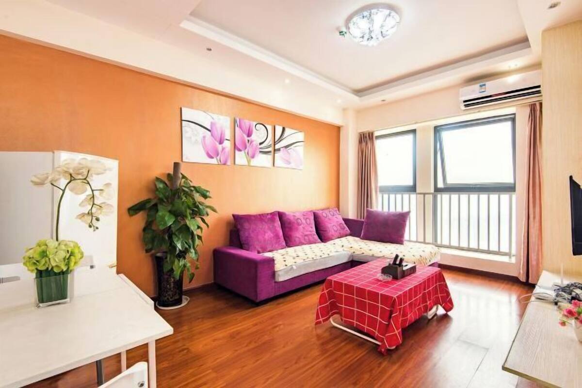 A modern living room with a purple sofa, a red table, and a large window.